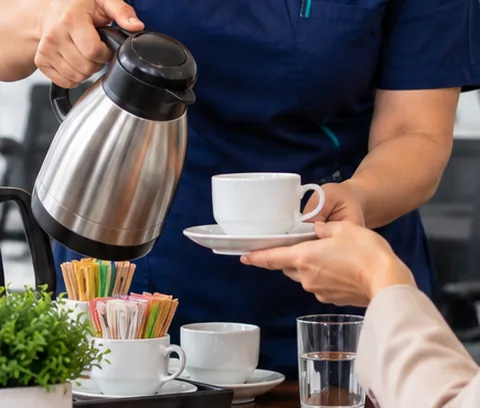 Detalle de cafetería con termo y tazas en un espacio de trabajo